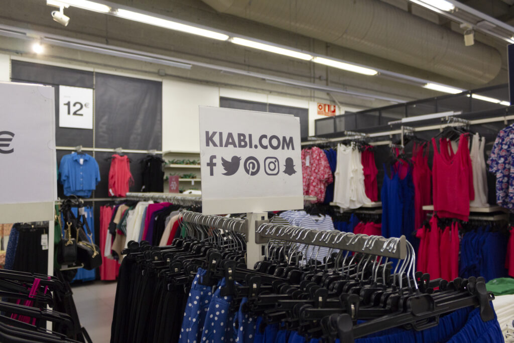 Interior de tienda Kiabi Parque Guadaíra Cartel sobre perchero de la tienda